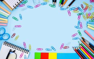 Colorful school stationery lie in the shape of a frame on blue background. Back to school. Flatlay composition. Top view. Copy space. photo