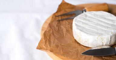 French soft cheese with white mold Camembert, knife and fork on the table. Breakfast concept. Close-up. Copy space. Selective focus. photo