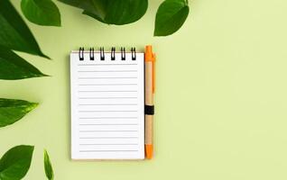 Notebook and pen made of eco friendly materials on a green background. Zero waste, recyclable. Top view. Copy space. photo