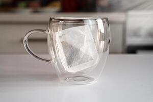 Empty mug and tea bag on the table at the kitchen. Tea drinking concept. Close-up. Selective focus. photo