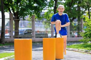 Senior Asian man is stretching his leg muscle during warm up exercise work out in the morning at public park for healthy and longevity concept photo