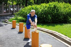 Senior Asian man is stretching his leg muscle during warm up exercise work out in the morning at public park for healthy and longevity photo