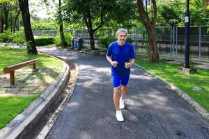 Senior Asian man is doing running exercise work out in the morning at public park for healthy and longevity concept photo