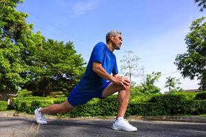 Senior Asian man is stretching his leg muscle during warm up exercise work out in the morning at public park for healthy and longevity concept photo