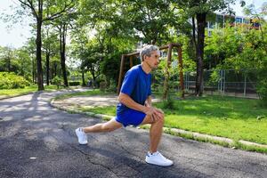 Senior Asian man is stretching his leg muscle during warm up exercise work out in the morning at public park for healthy and longevity photo
