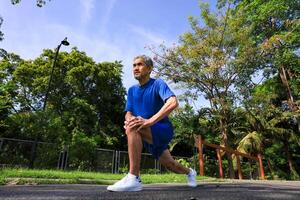 Senior Asian man is stretching his leg muscle during warm up exercise work out in the morning at public park for healthy and longevity concept photo
