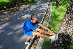 Senior Asian man is stretching his leg muscle during warm up exercise work out in the morning at public park for healthy and longevity concept photo