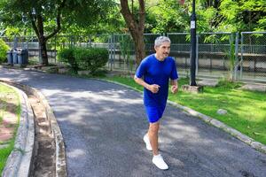 Senior Asian man is doing running exercise work out in the morning at public park for healthy and longevity concept photo