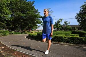 Senior Asian man is stretching his leg muscle during warm up exercise work out in the morning at public park for healthy and longevity photo