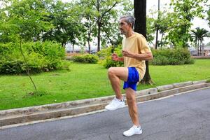 Senior Asian man is stretching his leg muscle during warm up exercise work out in the morning at public park for healthy and longevity photo