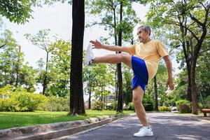 Senior Asian man is stretching his leg muscle during warm up exercise work out in the morning at public park for healthy and longevity photo