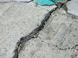 cement surface has collapsed and developed cracks, indicating deterioration of the road or walkway surface. photo