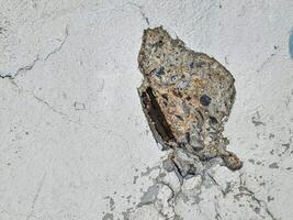 closeup view of a concrete surface with a large, Revealing the steel structure inside photo