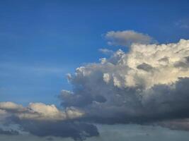 serene sky filled with an array of clouds. These clouds, white with hints of gray, are scattered across the blue canvas of the sky, illuminated by sunlight from the side. photo