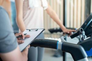 woman is running on Treadmills, trainer record and advice for exercisers and are checking how to exercise properly. correct exercise. diet, body shape, healthy, strong, care, gym, fitness, vacation photo