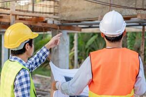inspector or engineer is inspecting construction and quality assurance new house using a blue print. Engineer or architects or contactor work to build the house before handing it over to the homeowner photo