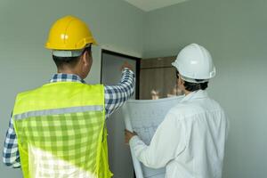 inspector or engineer is inspecting construction and quality assurance new house using a blue print. Engineer or architects or contactor work to build the house before handing it over to the homeowner photo