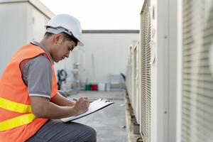 Asian maintenance engineer works on the roof of factory. contractor inspect compressor system and plans installation of air condition systems in construction. Checklist, inspector, control photo