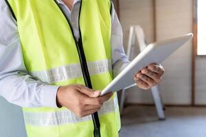 inspector or engineer is inspecting construction and quality assurance new house using a tablet. Engineers or architects or contactor work to build the house before handing it over to the homeowner photo