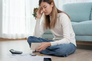 Stressed and headache asian woman with large bills or invoices no money to pay to expenses and credit card debt. shortage, Financial problems, mortgage, loan, bankruptcy, bankrupt, poor, empty wallet photo