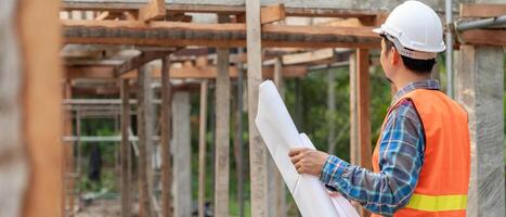 inspector or engineer is inspecting construction and quality assurance new house using a blue print. Engineer or architects or contactor work to build the house before handing it over to the homeowner photo
