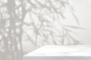 White Marble Table Corner with Light Beam, Shadow of Japanese Bamboo Tree and Spotlight on the White Concrete Wall Background photo