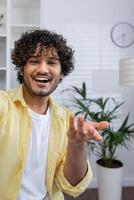 Smiling man making a call from home, joyfully engaging in conversation. Indoor setting with plants and a clock in the background. photo