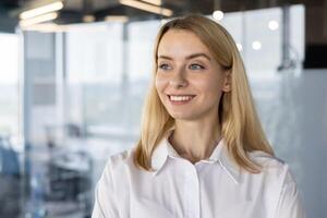 Portrait of a confident female business professional with a sincere smile, standing in a well-lit modern office. This image highlights professionalism, success, and positive workplace environment. photo
