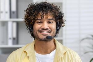 Smiling customer service representative wearing headset, looking at the camera in a modern office setting, ready to assist customers. photo