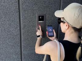 Close up of woman using intercom at building entrance. photo