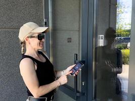 Woman locking smartlock on the entrance door using a smart phone. Concept of using smart electronic locks with keyless access. photo