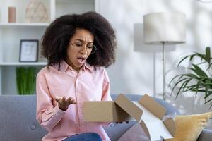 Woman with a surprised and puzzled expression opening an empty cardboard box at home. Concept of expectation, disappointment, and online shopping. photo