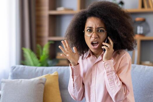 un mujer demostración frustración mientras hablando en el teléfono, sentado en un cómodo sofá en un acogedor hogar interior. foto