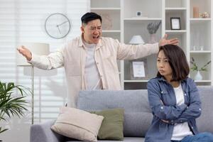 Man upset and yelling, gesturing with frustration, while a woman sits calmly appearing indifferent or tired of the argument. The setting is a modern living room , photo