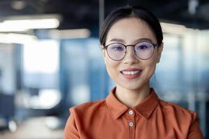 Confident Asian businesswoman wearing glasses standing in a modern office environment. Capturing professionalism, confidence, and business attire. photo