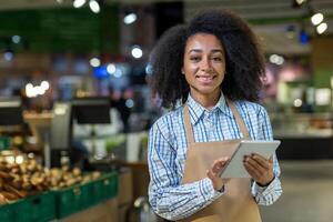 Happy grocery store employee using a digital tablet while working in a modern supermarket. Captures the joy and efficiency in retail environment. photo