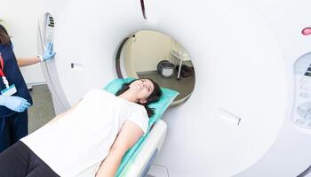 CT scan technologist overlooking patient in Computed Tomography scanner during preparation for procedure. Woman patient going into CT scanner. photo