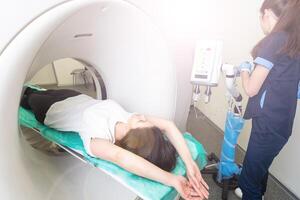 CT scan technologist overlooking patient in Computed Tomography scanner during preparation for procedure. Woman patient going into CT scanner. photo