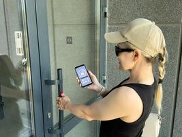Close up of woman using intercom at building entrance. photo