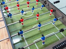 Classic Foosball Table Game With Players in Red and Blue Jerseys During Daytime Indoor Match. Close-up view of foosball table featuring red and blue jersey players positioned for daytime indoor game. photo