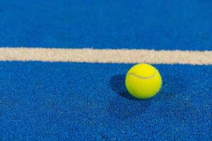 ball next to the line on a blue paddle tennis court photo