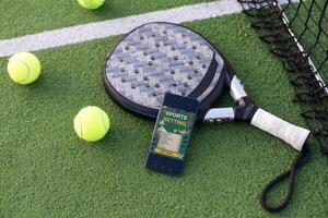 A tennis ball, a racket and a mobile phone with a put screen lie on a blue background. The concept of advertising a tennis club or ordering services. Horizontal photo