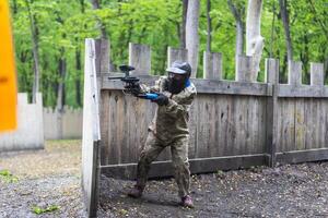 Paintball game. Players with weapons shooting paint balls. Men on the playground. Guys in camouflage and masks are fighting. photo