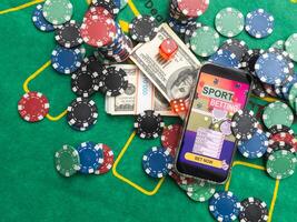 online casino smartphone with poker chips device over green table photo