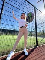 positivo niña mirando a cámara mientras jugando padel a Corte al aire libre foto