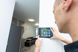 Worker with tablet computer checking alarm system indoors photo