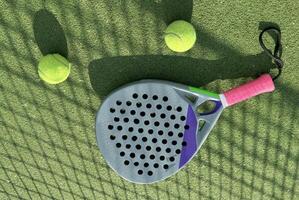 Paddle racket with a ball ready to play the fastest growing sport in recent years worldwide. Padel court in summer, the perfect time to practice this sporting discipline and release stress. photo