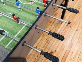 Classic Foosball Table Game With Players in Red and Blue Jerseys During Daytime Indoor Match. Close-up view of foosball table featuring red and blue jersey players positioned for daytime indoor game. photo
