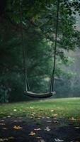 Empty swing in serene park, surrounded by lush greenery and fallen leaves Vertical Mobile Wallpaper photo