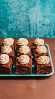 Tray of fudge squares on brown surface with cream swirls, perfect for National Fudge Day Vertical Mobile Wallpaper photo